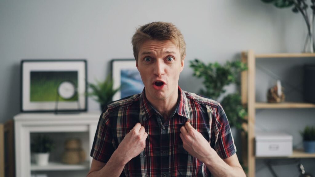 Young man expressing surprise indoors with a modern and stylish background.