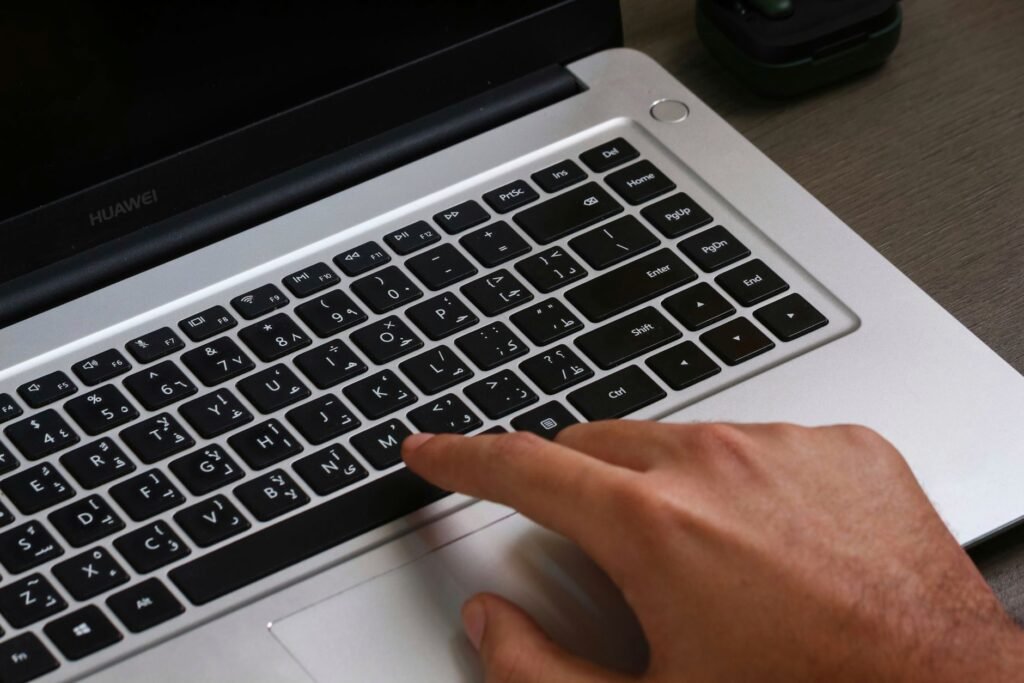Fingers on a laptop keyboard with Arabic text, showcasing modern technology.