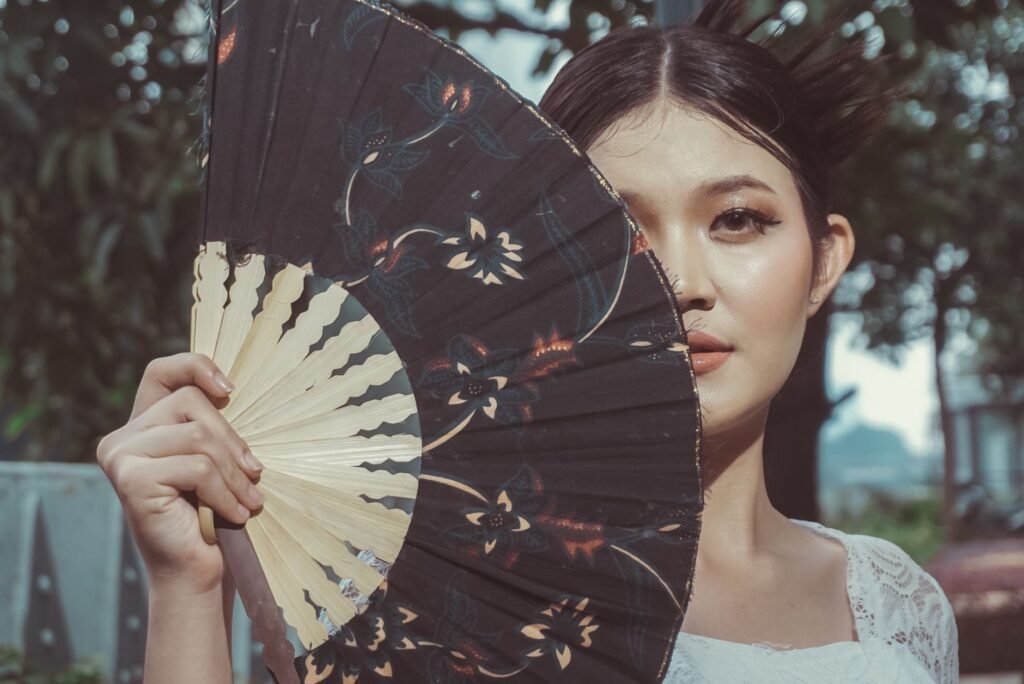 Half-face portrait of a woman holding an ornamental fan in Central Jakarta.