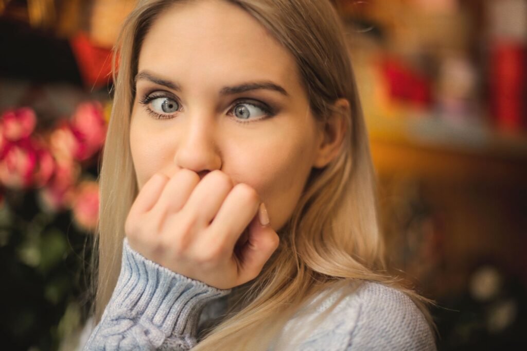 A blonde woman makes a silly face indoors, showcasing a playful and humorous expression.