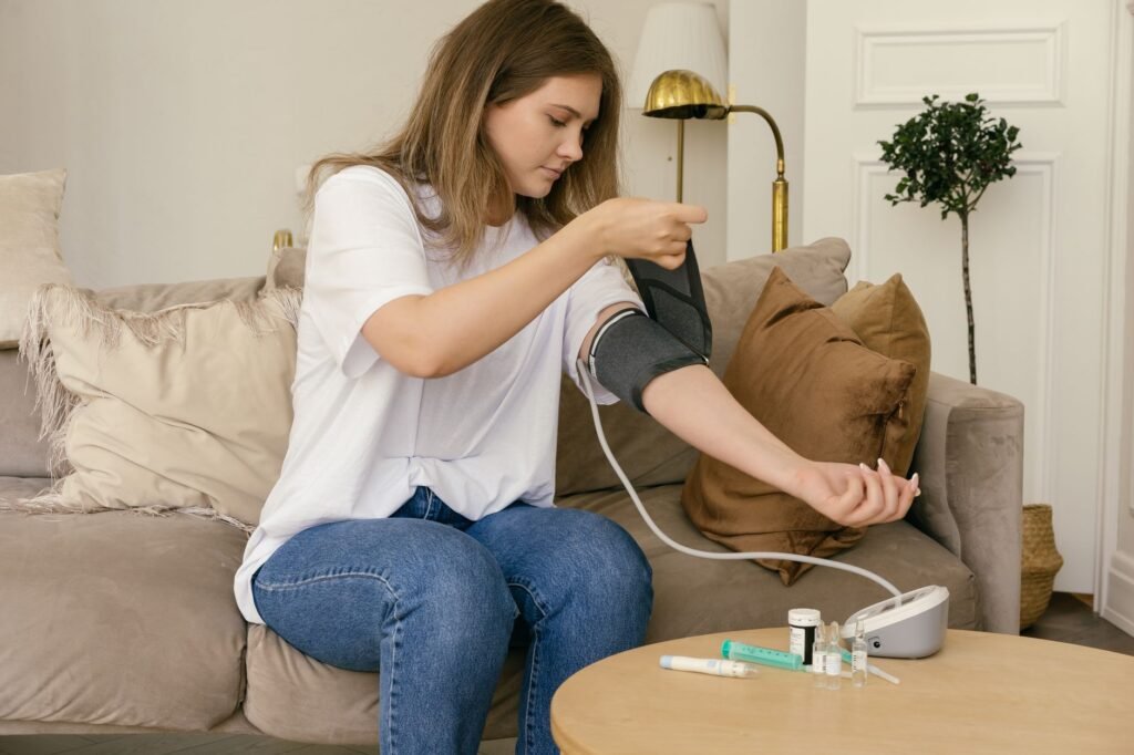 A woman uses a digital blood pressure monitor sitting on a cozy couch.
